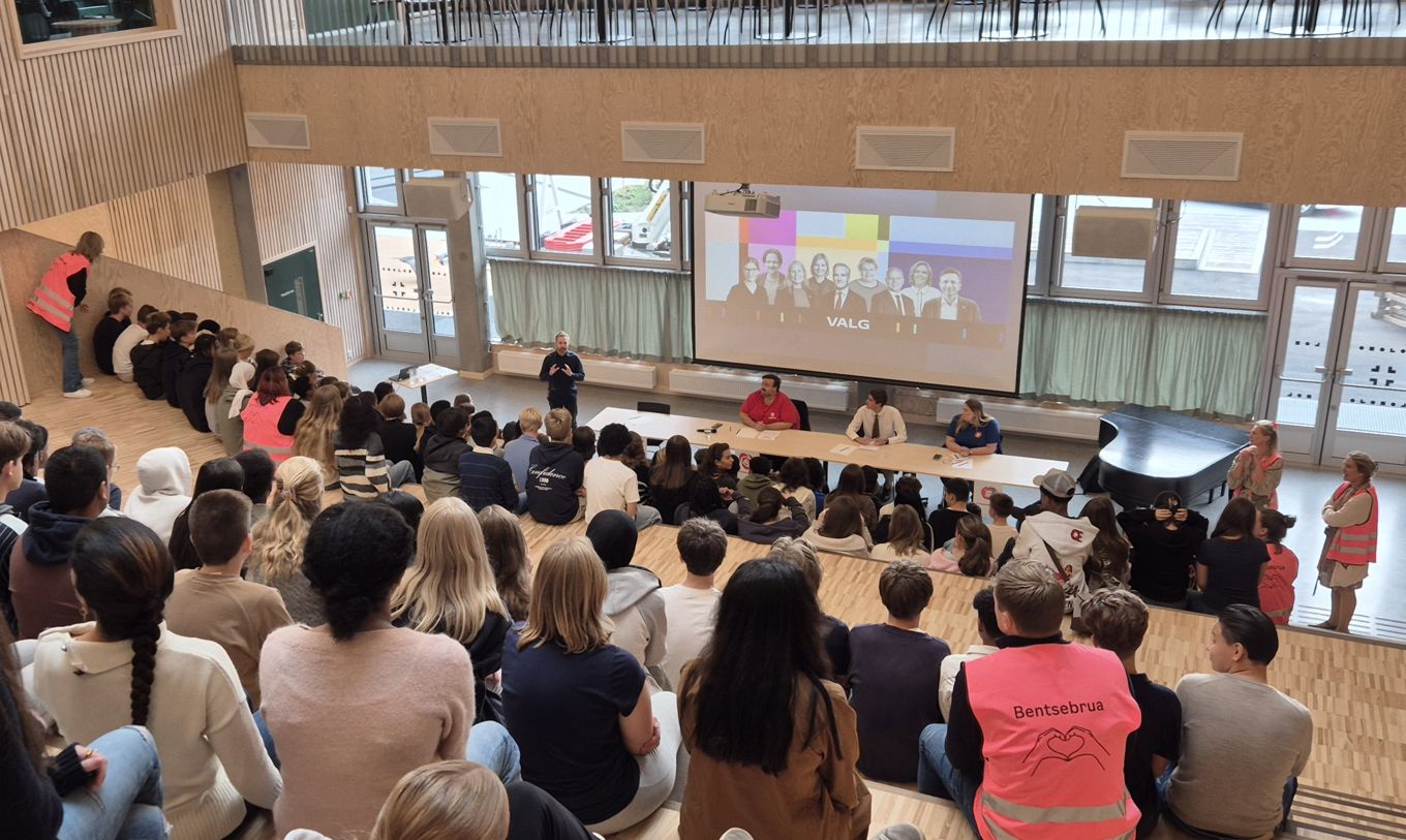 en gruppe mennesker som sitter i et rom med en stor skjerm